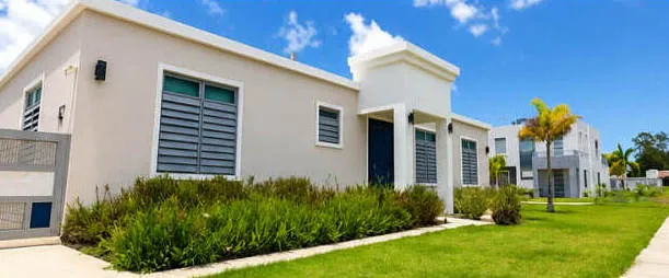 Casa de concreto con techo plano y jardín en una urbanización de Puerto Rico