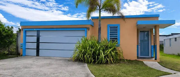 Casa residencial de concreto con marquesina y palma en Puerto Rico