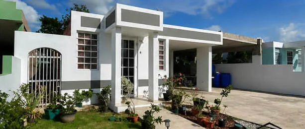 Casa puertorriqueña de concreto con rejas ornamentales y patio de cemento